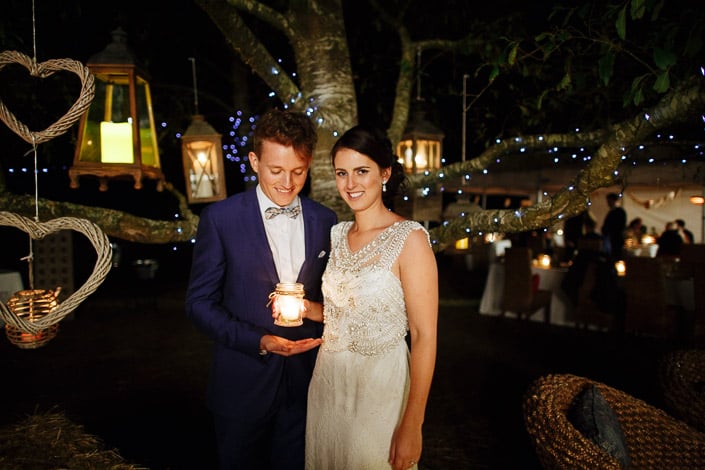 The couple hold a candle jar beneath the lantern tree at Pennyroyal Otways Retreat