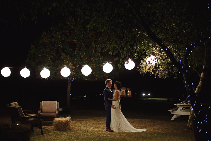 The couple embrace beneath the paper lanterns at Pennyroyal Retreat