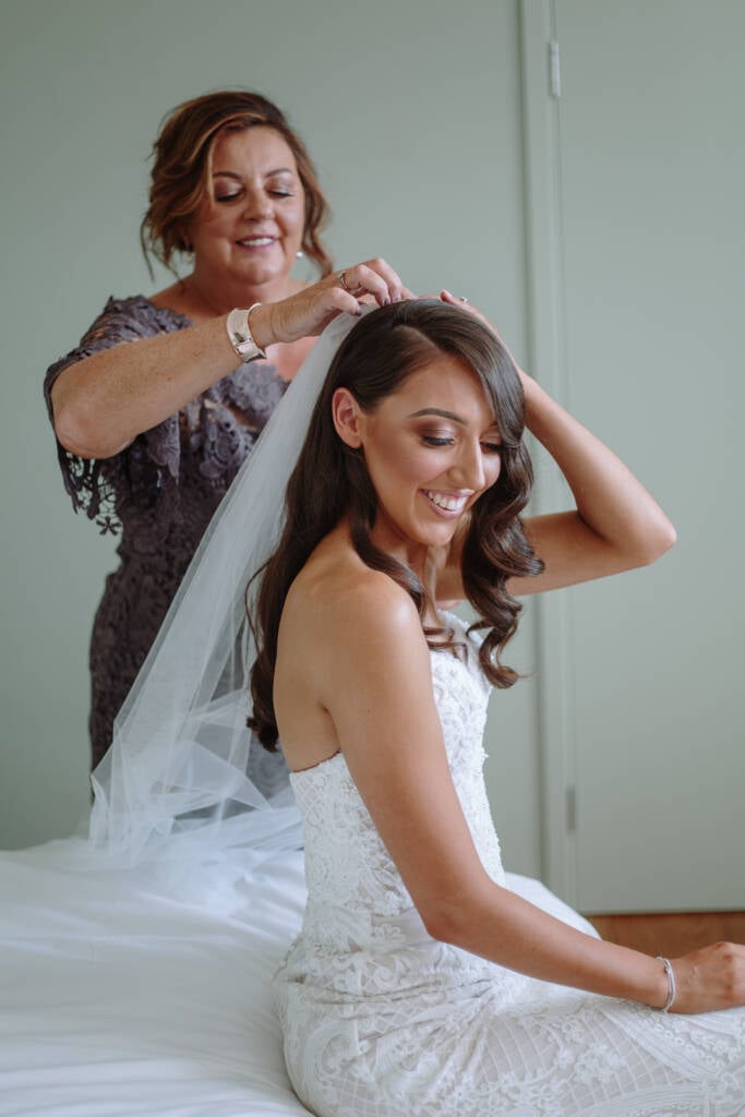 Georgia smiles as a helper arranges her veil in her hair.