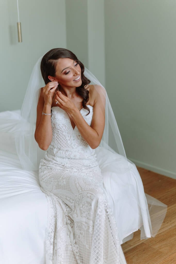 Georgia adjusts her earring during bridal preparation.