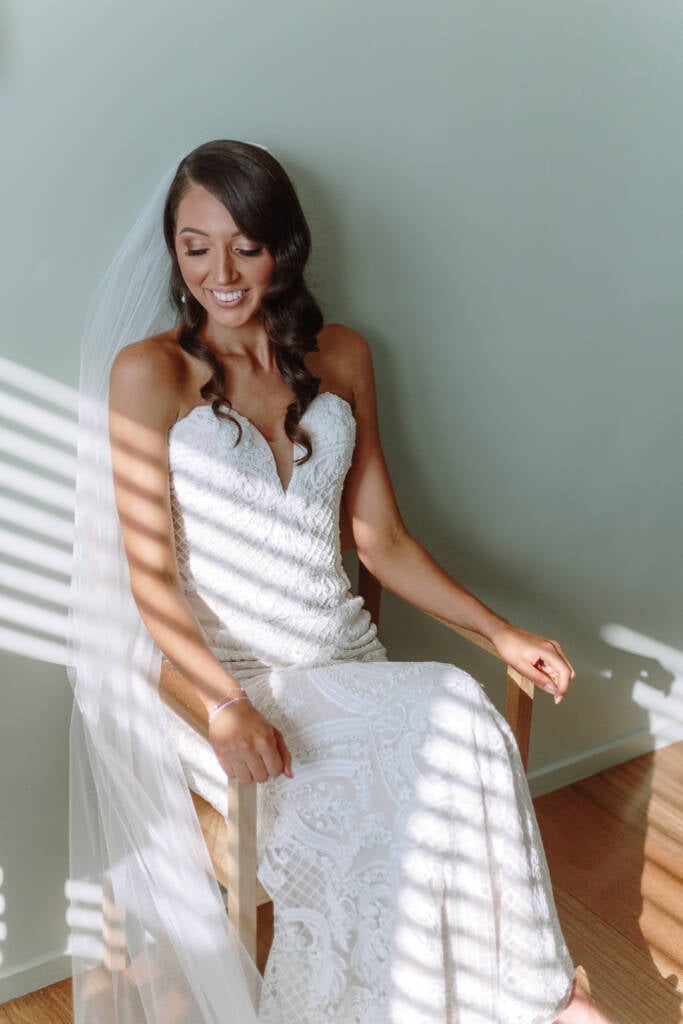 Georgia sits in a timber chair with striped sunlight across her gown at The Prince Deck.