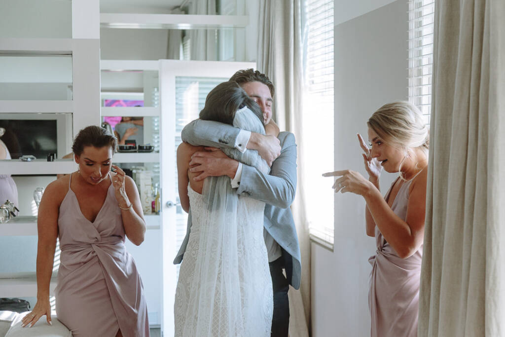 Georgia hugs a guest in a grey jacket as her bridesmaids watch.