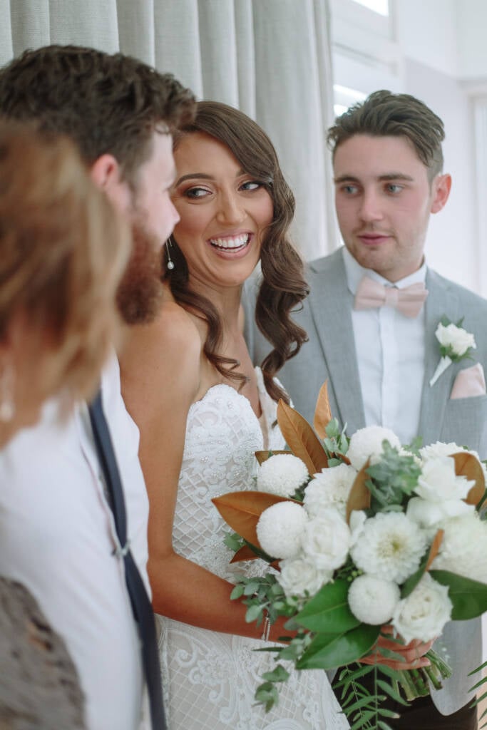 Georgia smiles with guests while holding her white bridal bouquet.