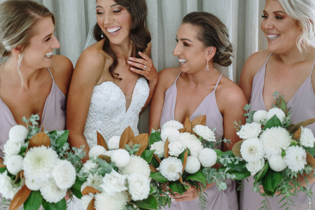 Georgia and three bridesmaids pose together with white bouquets and lilac dresses.