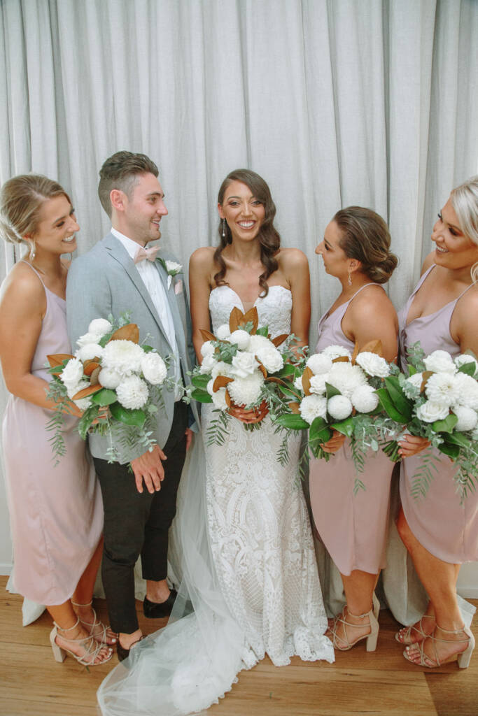 Georgia poses with her bridesmaids and a guest in a grey jacket.