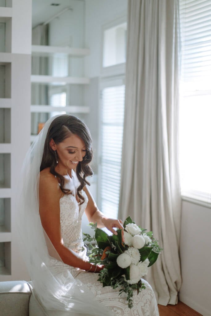 Georgia looks down at her white bouquet beside the window at The Prince Deck.