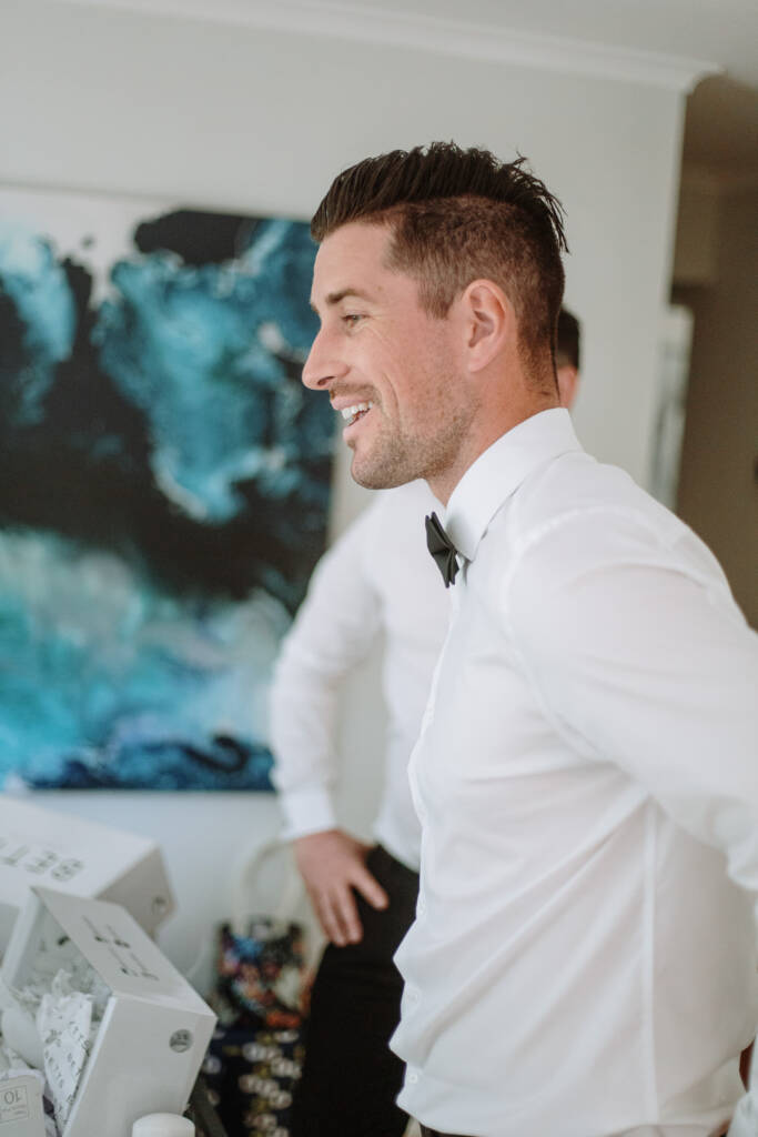 Michael smiles in profile wearing a white shirt and black bow tie.