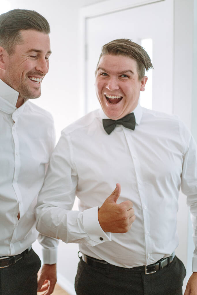 Michael gives a thumbs-up while laughing with a companion during groom preparation.