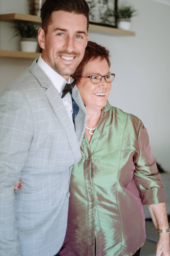 Michael smiles beside a guest in a green jacket during preparation.