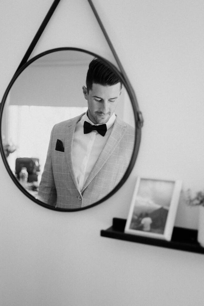 Michael looks down in a close black-and-white mirror portrait at home.