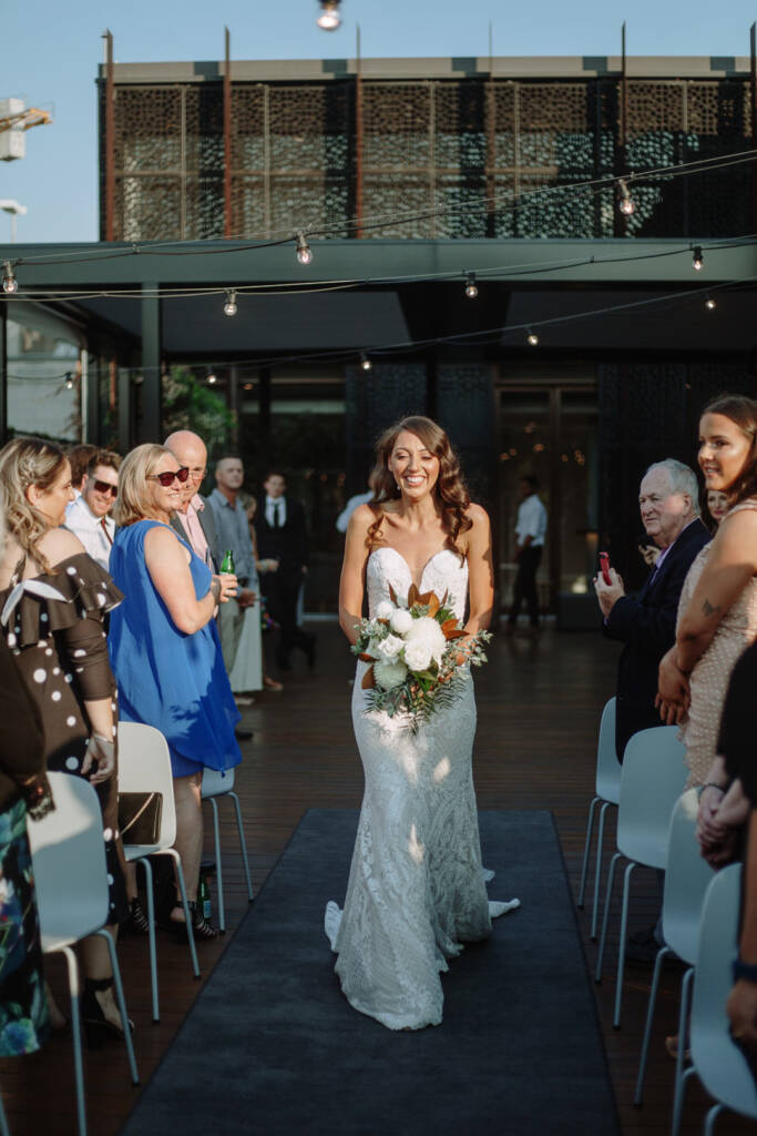 Georgia walks down the aisle alone, carrying her white bouquet at Prince Deck.