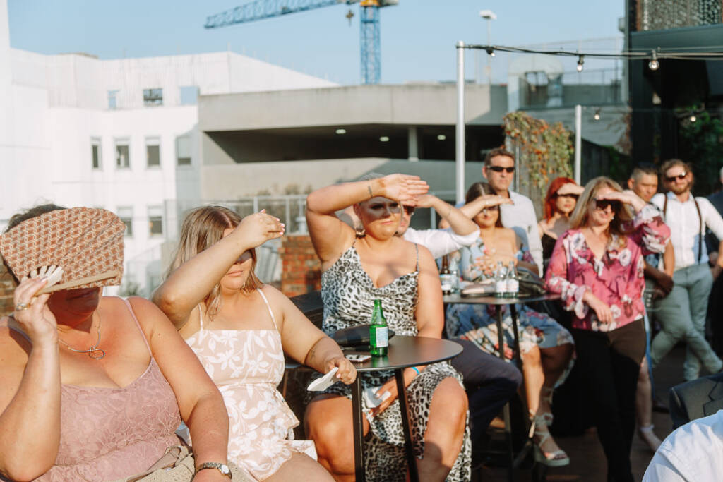 Guests shade their eyes from the afternoon sun during the ceremony at The Prince Deck.
