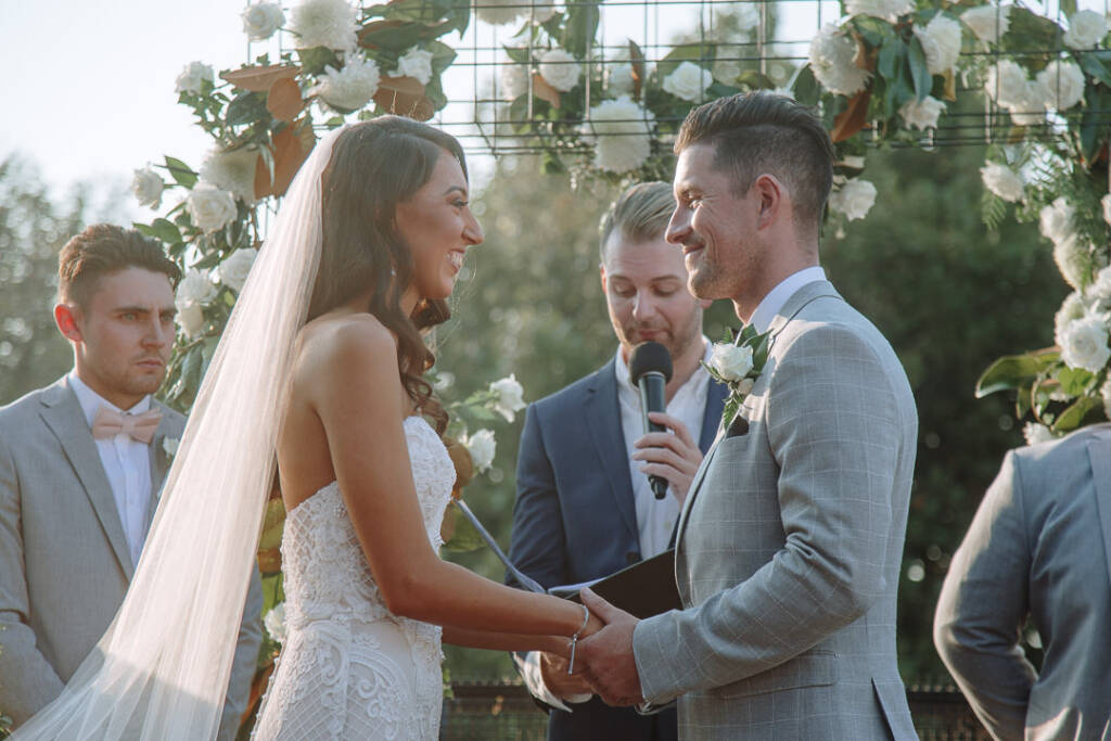 Georgia and Michael smile while their celebrant reads from a folder at Prince Deck.