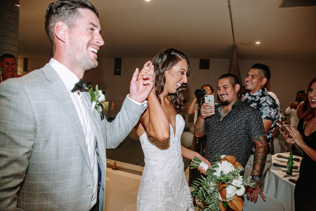 Georgia and Michael raise their joined hands as they enter the indoor reception at Prince Deck.