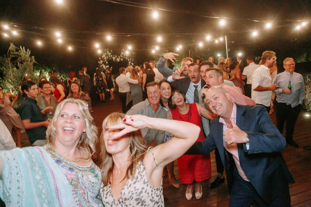 Guests smile and raise their hands towards the camera during the party at Prince Deck.