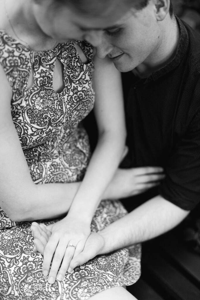 From above, their hands rest together on a paisley skirt, a solitaire ring catching the light.