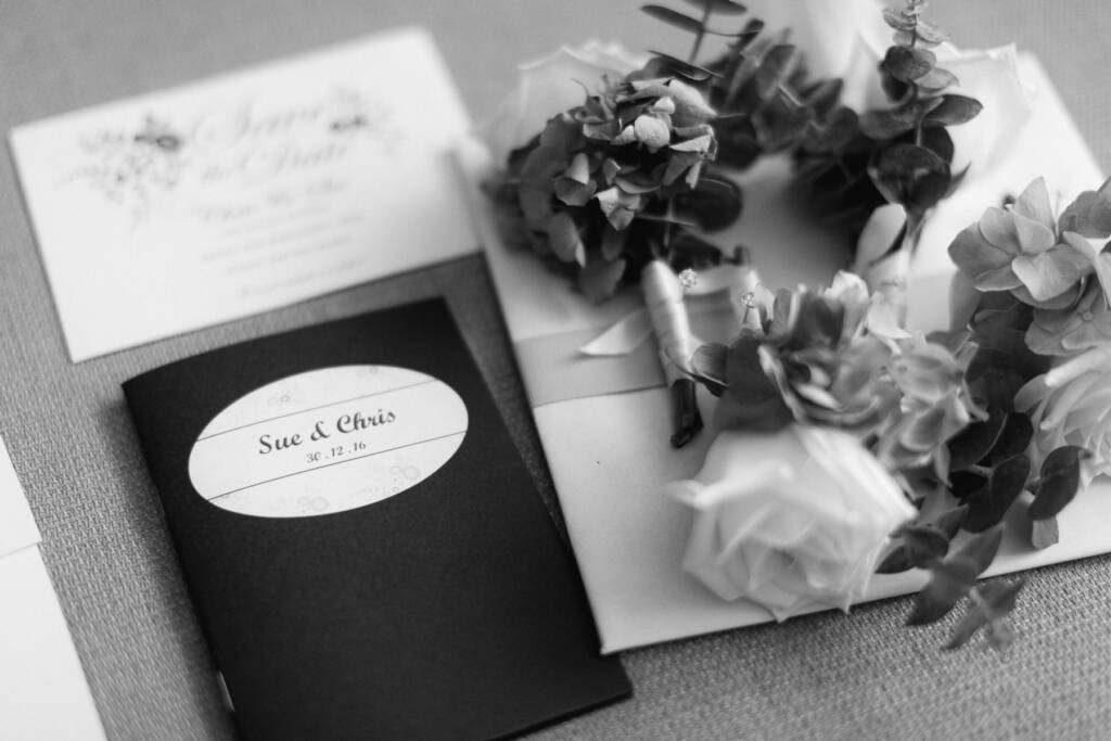 Sue and Chris's wedding stationery and pinned buttonholes arranged in a flat lay.