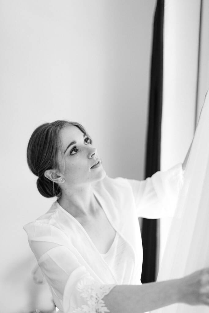 Sue looks up at the tulle gown as she lifts it from the window, pearl earring showing.