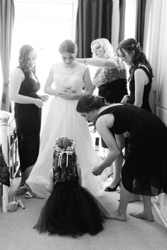 Attendants and a flower girl help arrange Sue's gown at her parents' home.