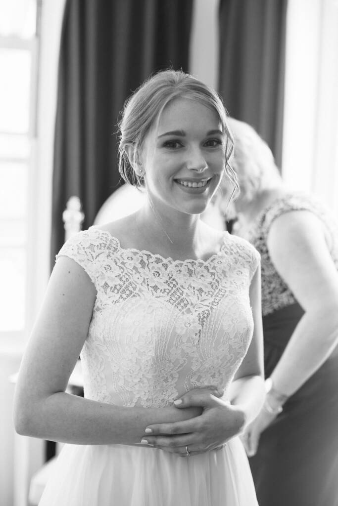 Black and white of Sue smiling at camera in the lace bodice while the back is fastened.