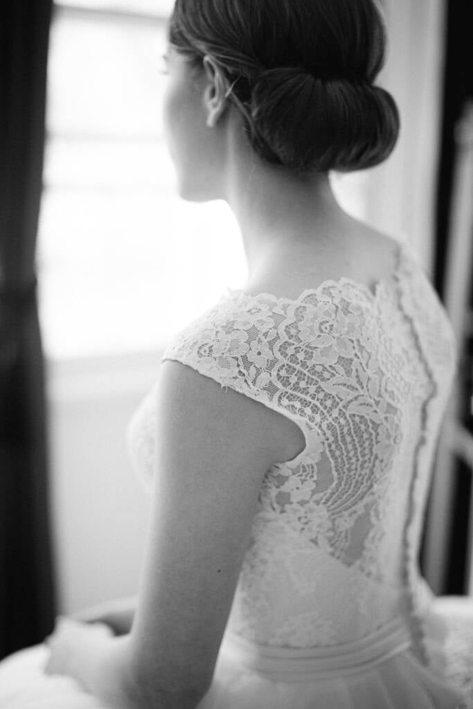 The lace back and cap sleeves of the gown from behind, Sue's chignon turned to the window.