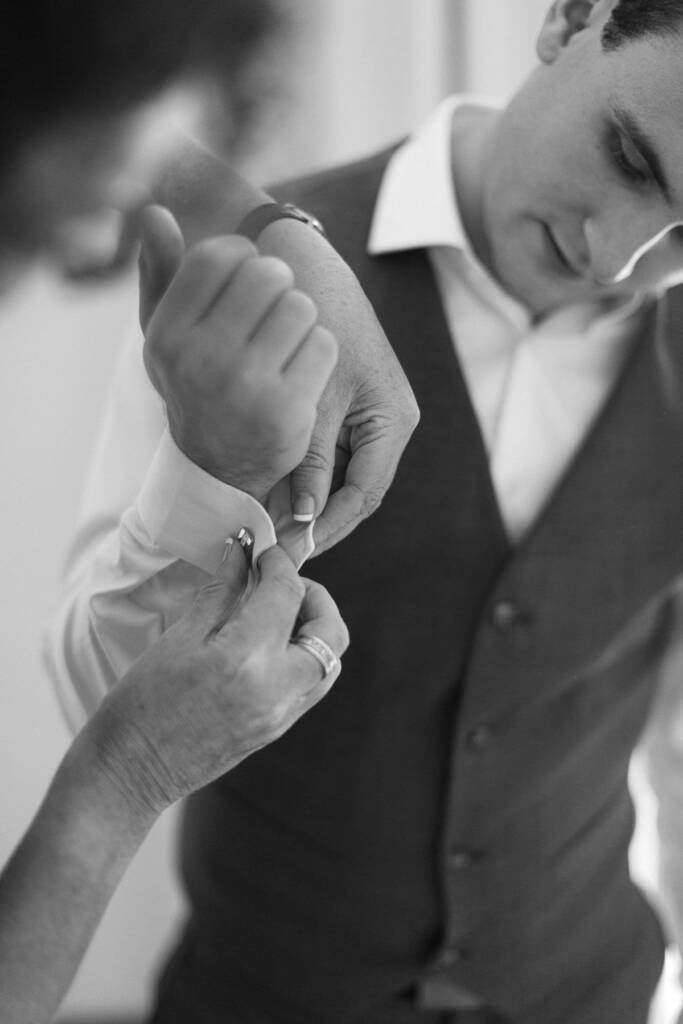 An adult fastens Chris's cufflink during groom preparations at his Mount Waverley home.