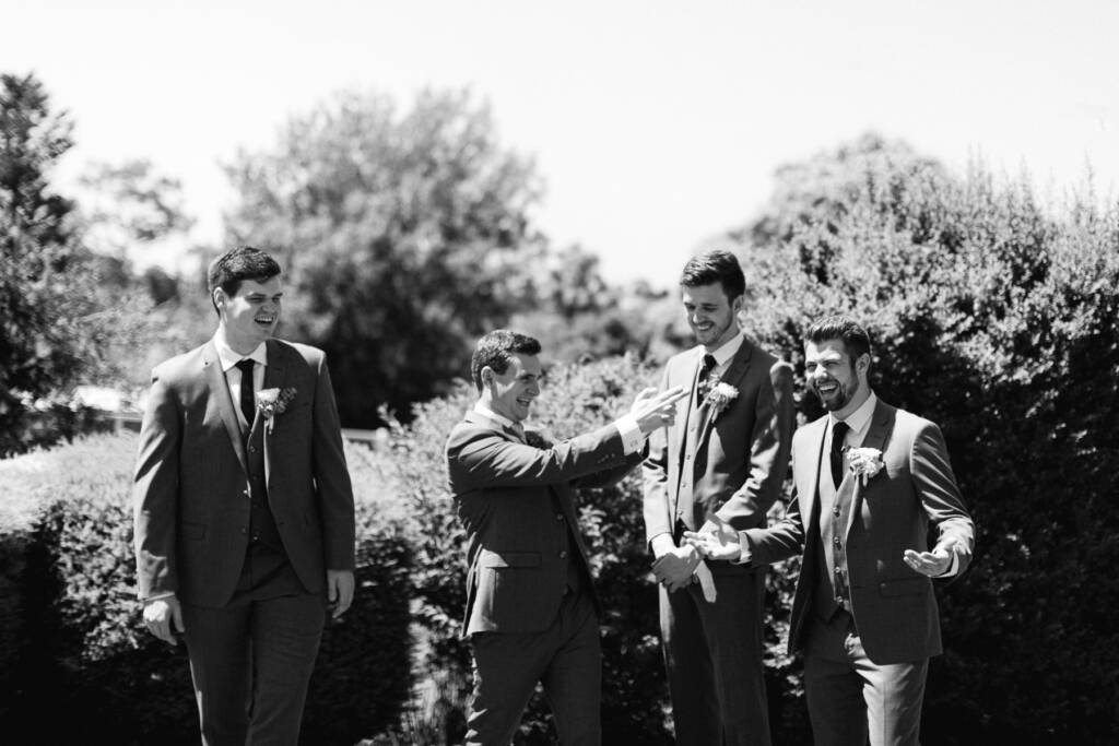 Chris and three suited attendants laugh beside a hedge outside his Mount Waverley home.