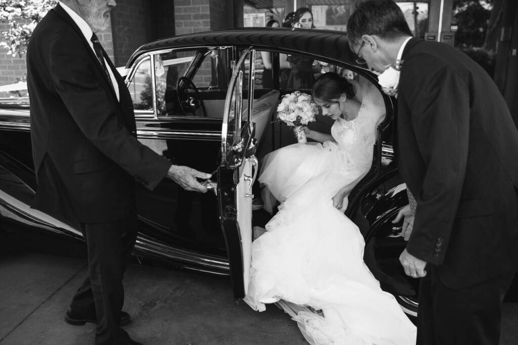 Sue steps from a classic car with her bouquet outside Syndal Baptist Church.