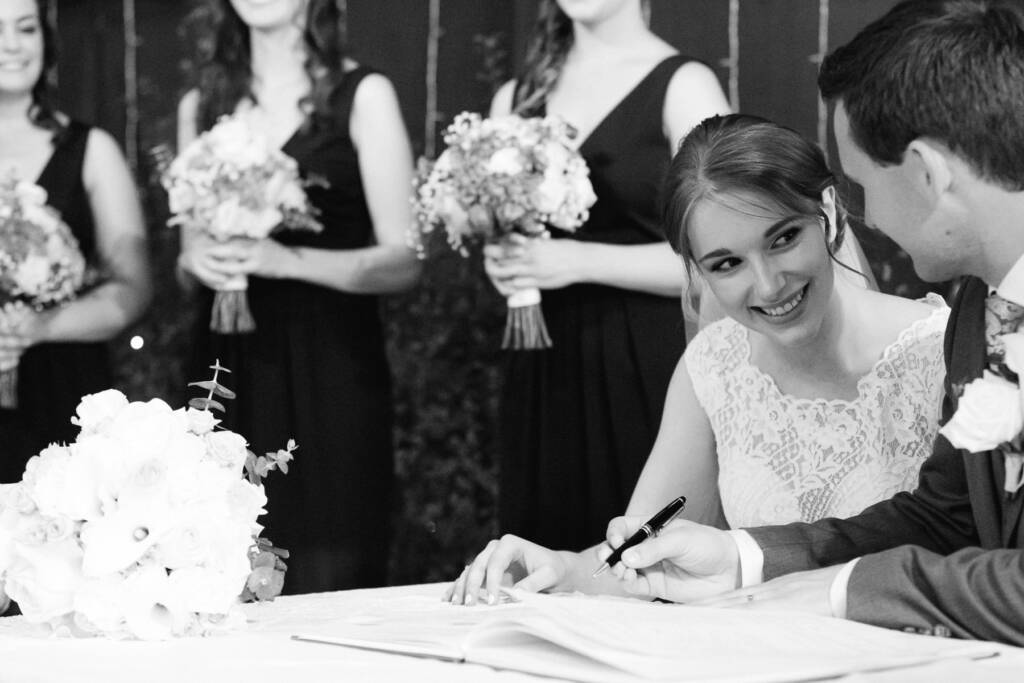 Chris holds a pen above the open marriage register while Sue smiles beside him at Syndal Baptist Church.