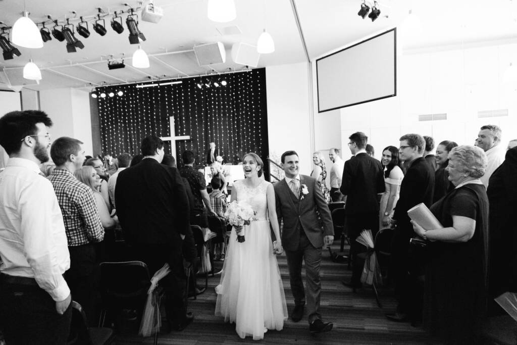 Sue and Chris walk hand in hand down the aisle at Syndal Baptist Church as guests stand.