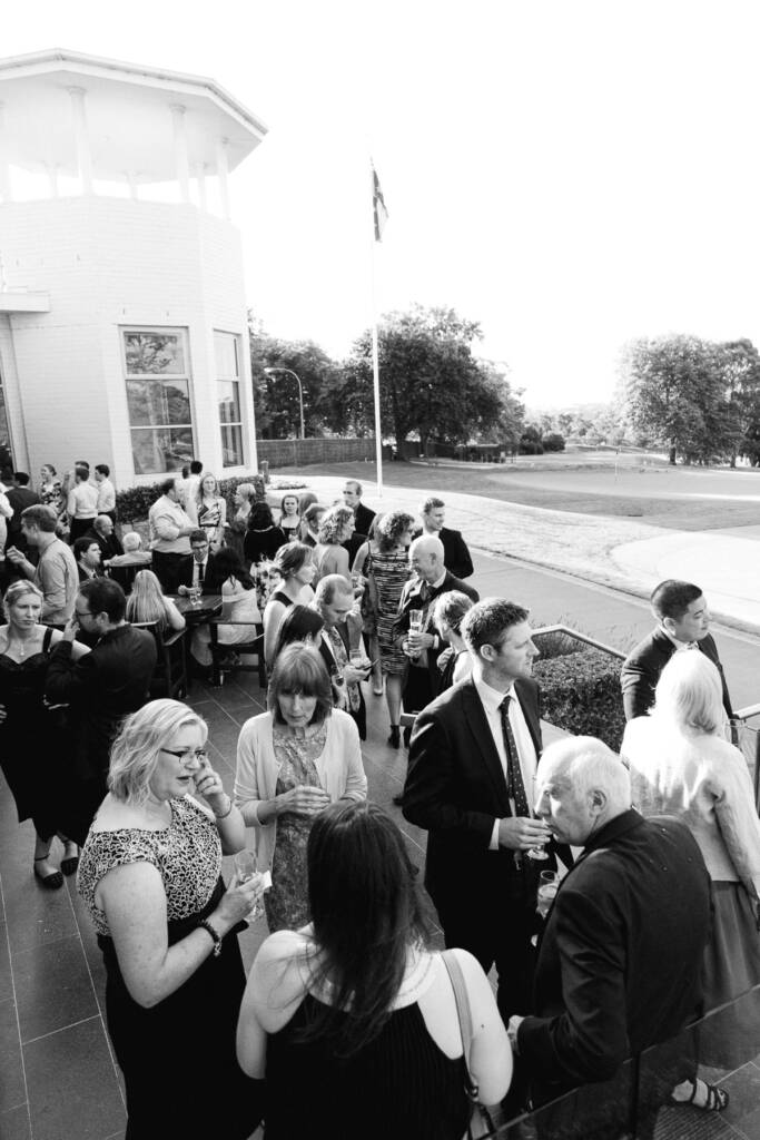 Guests mingle with drinks on the Riversdale clubhouse terrace overlooking the golf course.