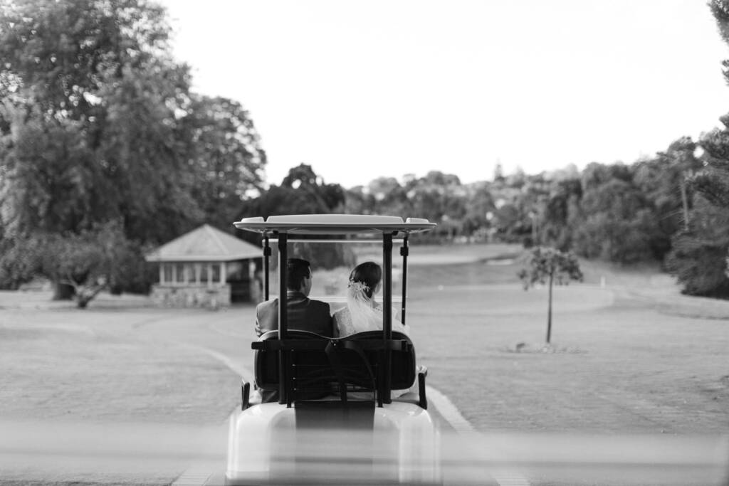 Sue and Chris ride in a golf buggy along a course path at Riversdale.