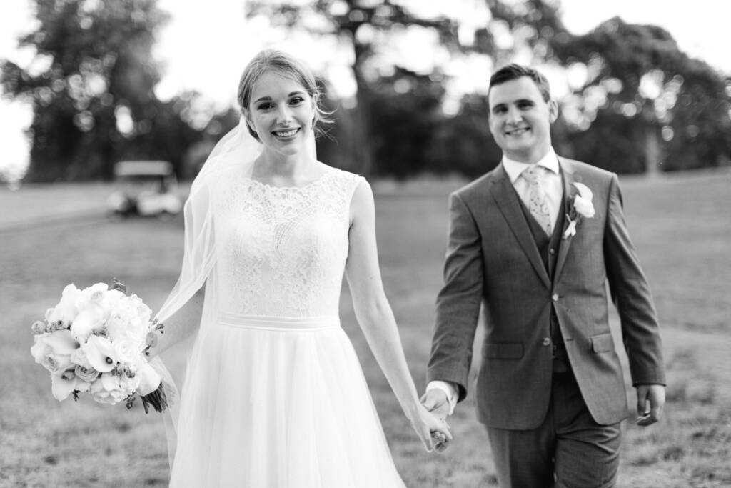 Sue and Chris hold hands on the Riversdale Golf Club fairway with a golf buggy behind them.