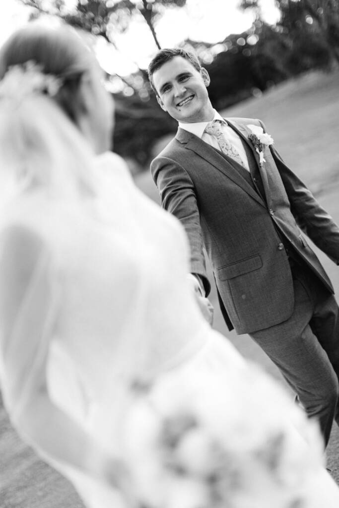 Chris smiles towards Sue while holding her hand on the grass at Riversdale.