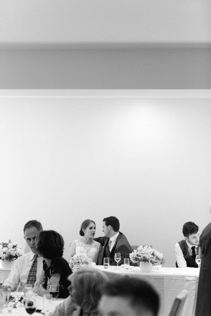 Sue and Chris talk at the Riversdale bridal table among low floral arrangements.