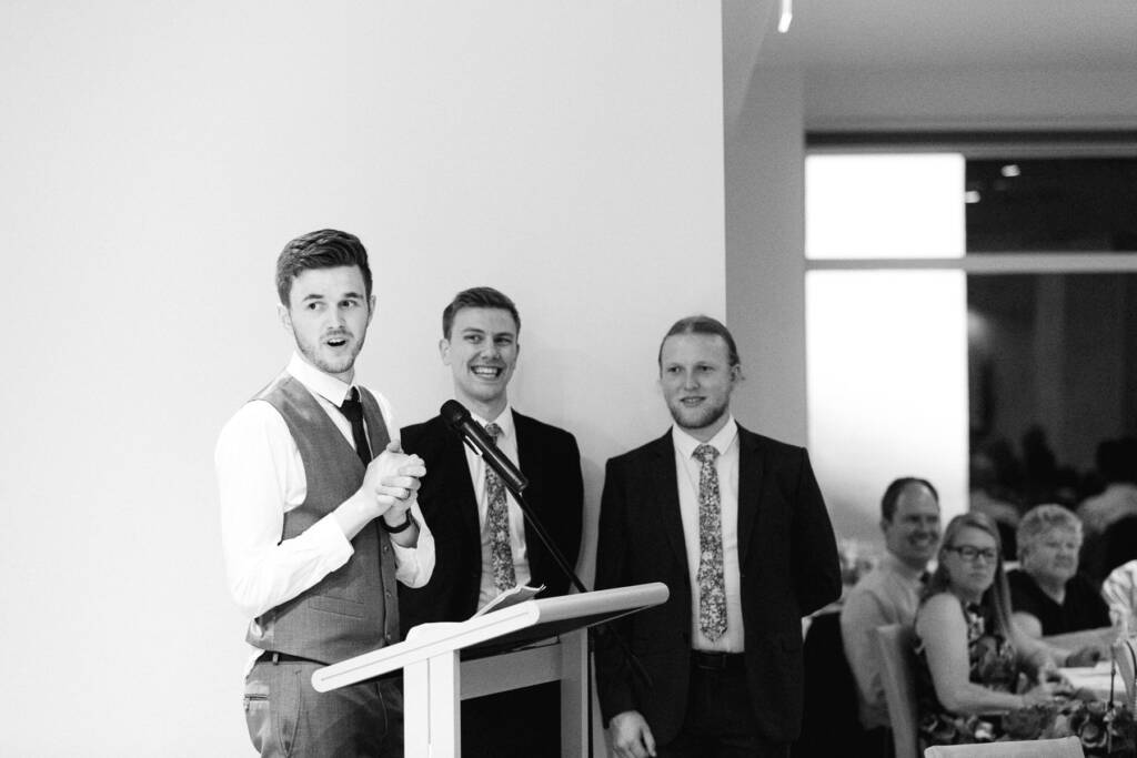 A speaker in a waistcoat talks at the lectern during the Riversdale Golf Club reception.