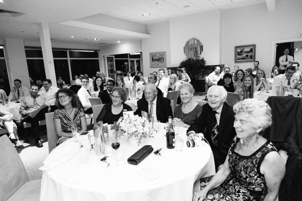 Guests smile at round reception tables near a stone fireplace at Riversdale.