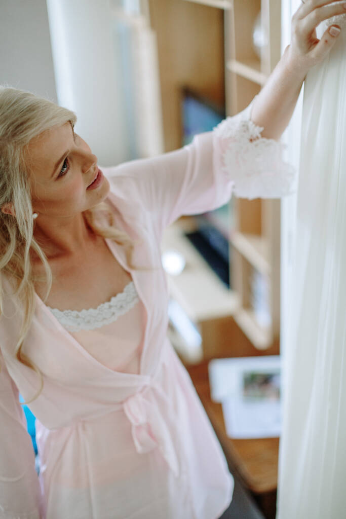 Kate touches her hanging wedding gown while wearing her getting-ready robe.
