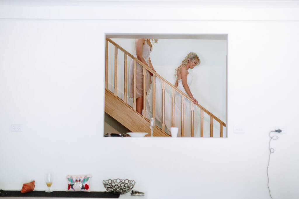Kate descends timber stairs with an attendant, framed through a wall opening at her Chum Creek Airbnb.