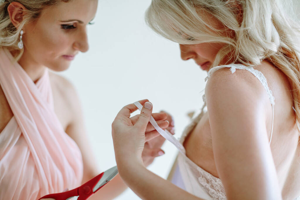 An attendant holds red scissors beside a ribbon on Kate's gown.