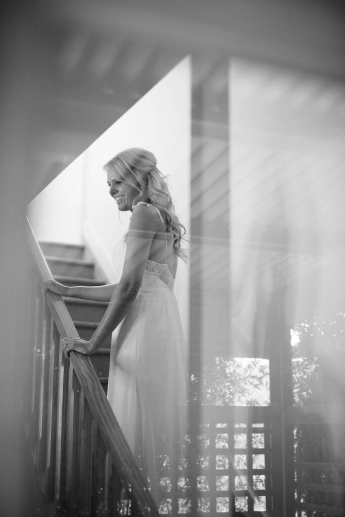 Black-and-white portrait of Kate at her Chum Creek Airbnb's stair rail, photographed through reflective glass.
