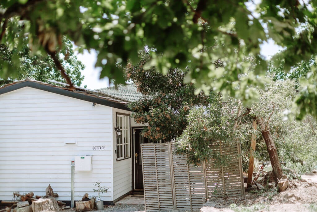 Ashlee's Healesville Airbnb has white weatherboards, timber screening and trees beside the entrance.