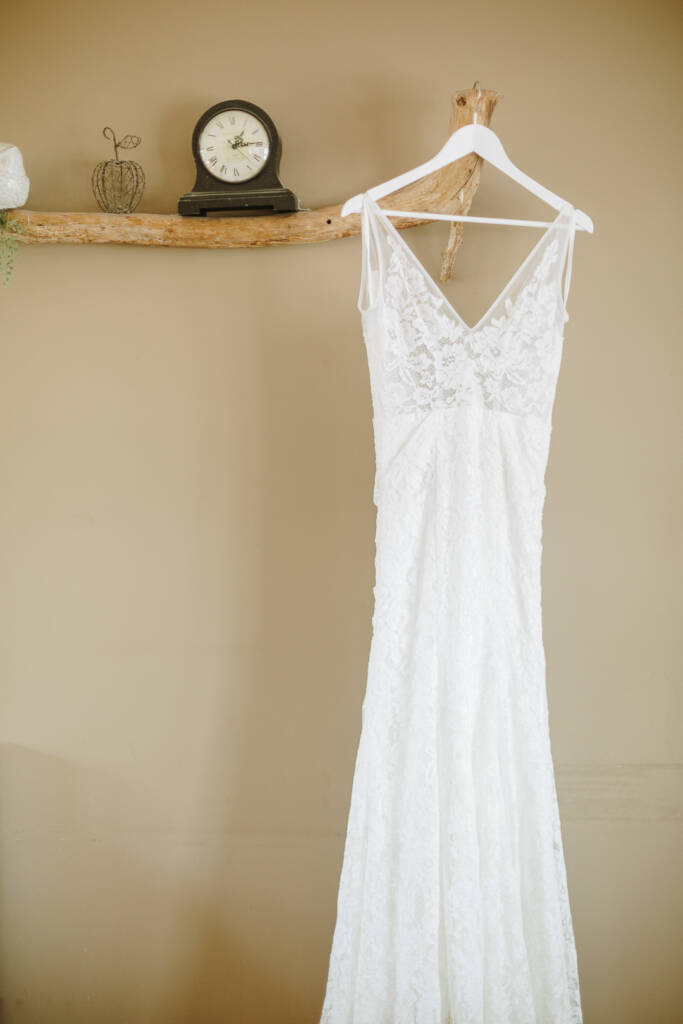 Ashlee's lace gown hangs from a rustic branch shelf beside a mantel clock at her Healesville Airbnb.