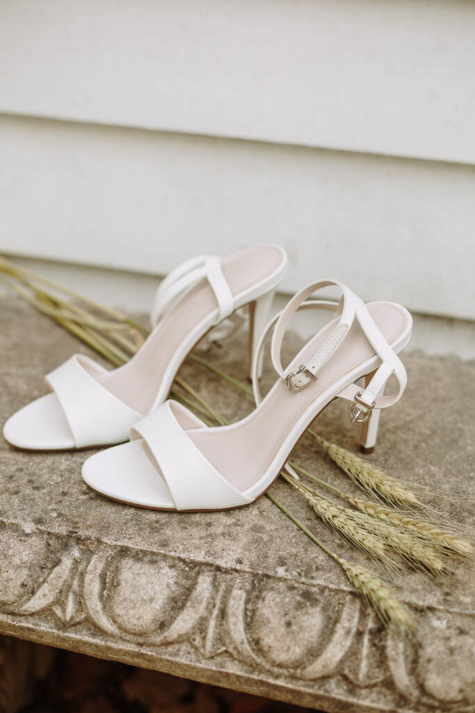 White bridal heels rest beside grain stalks on a carved stone bench at Ashlee's Healesville Airbnb.