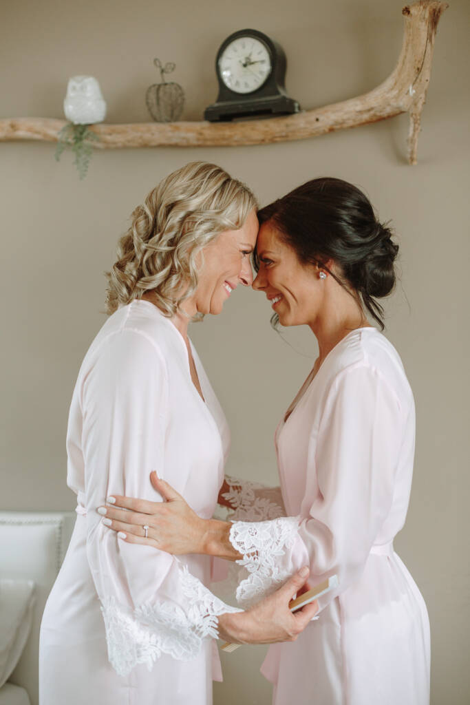 Ashlee and a companion touch foreheads and smile in their getting-ready robes.