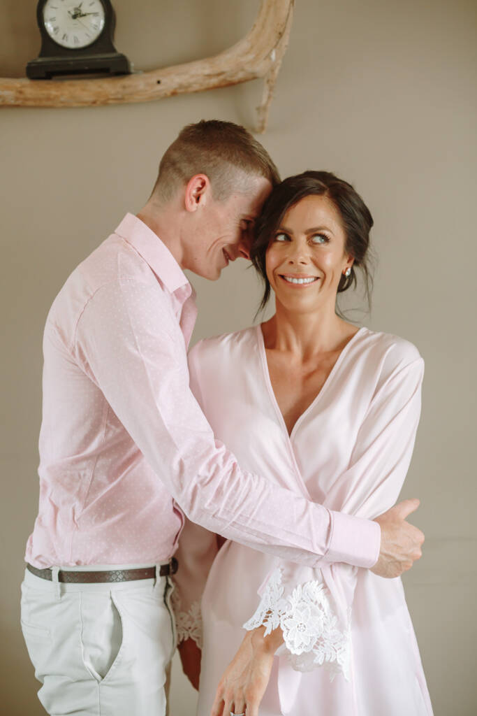 A guest in a pink shirt embraces Ashlee during preparation.