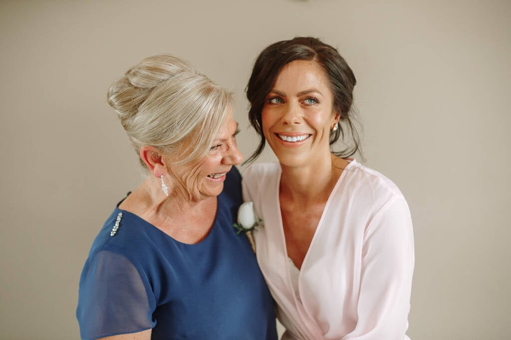 Ashlee smiles with an older guest wearing a blue dress and white corsage.
