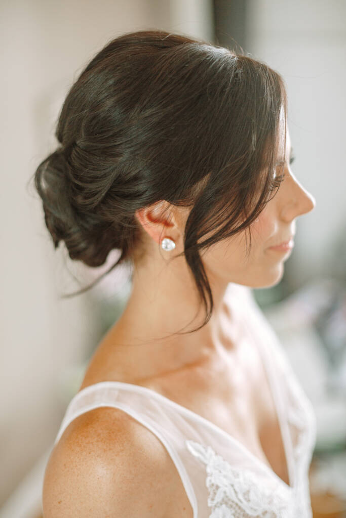 Close-up of Ashlee's low updo, stud earring and lace neckline.