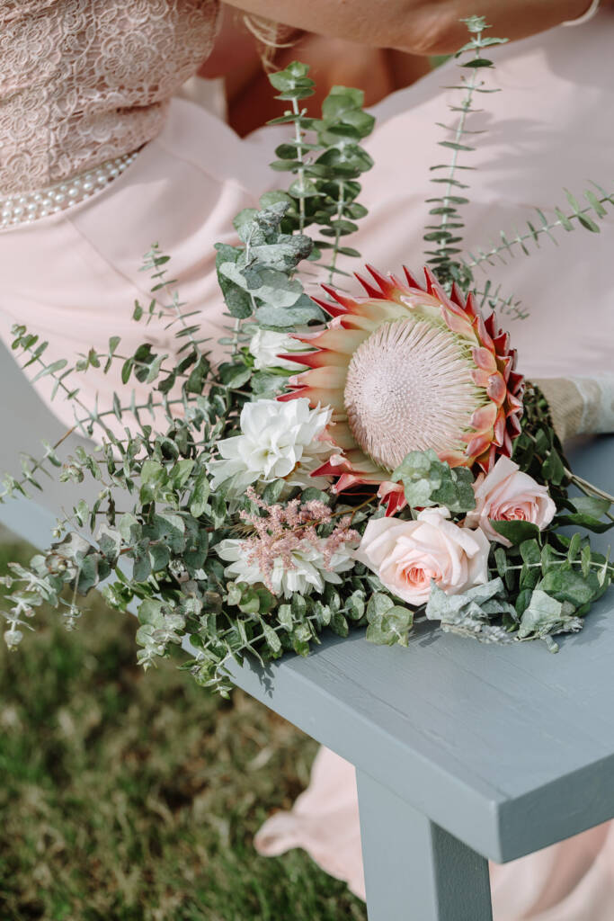 A king protea, pink roses and eucalyptus fill an attendant's bouquet at Riverstone.