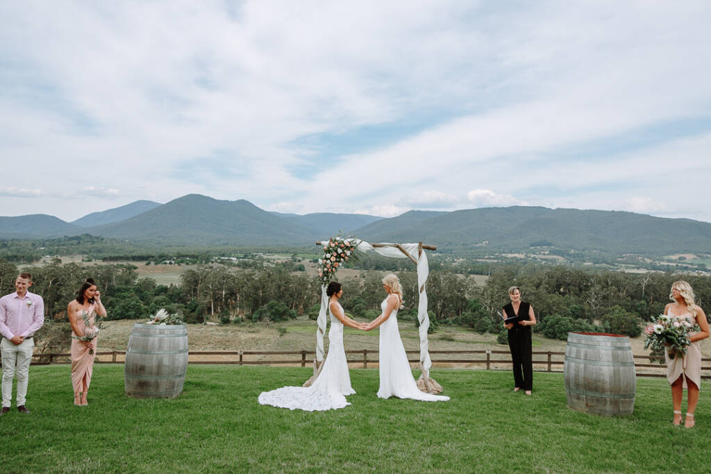 Ashlee and Kate hold hands during their Yarra Valley commitment ceremony at Riverstone.